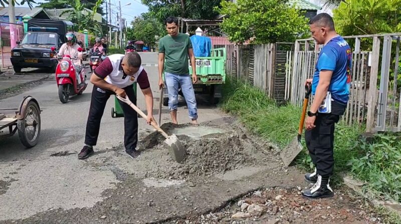 Personel Polsek Kuta Raja turun tangan memperbaiki jalan rusak dan berlubang atau rusak di gampong Lampaseh Kota, Banda Aceh, Jumat (1/12/2023). 